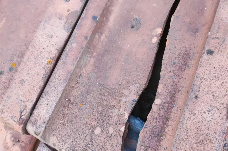 Tuile fissurée sur une toiture, point d'entrée d'infiltration